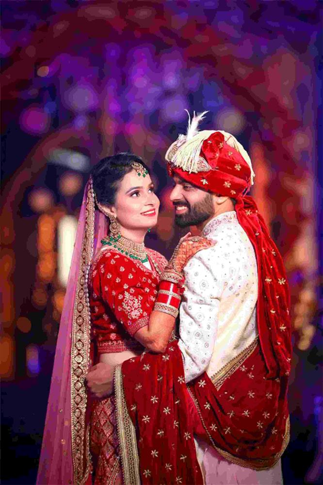 image of red lehenga with pink dupatta for bride and pink sherwani and red dupatta and pagdi for groom